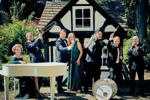 Photo of the Simply Swing Band, Ballroom & Latin American dance singers. A lady at a grand piano, a trombone player, singers, Saxophonist and a drummer