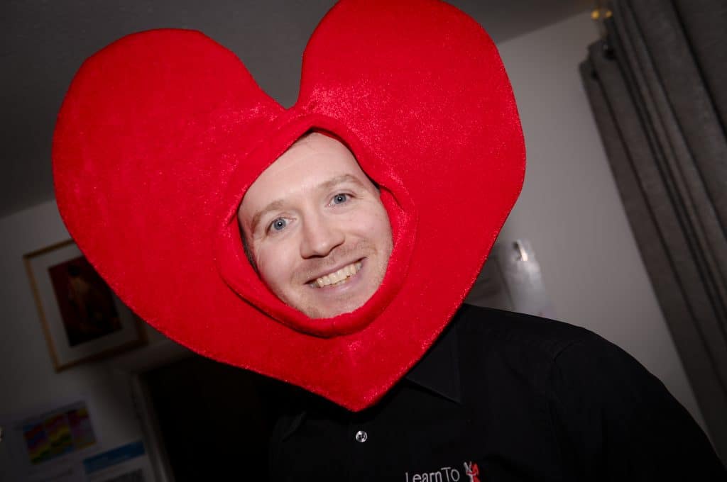 Antony from Learn To Dance wearing a headpiece with a large heart shape surrounding his face.