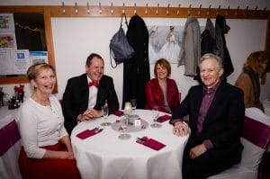 Four laughing adults sitting around a round table at our Valentine Dinner & Dance.