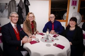 Four smiling adults sat around a circular table at our Learn To Dance Valentine Dinner & Dance.
