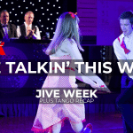 A couple dancing a Jive move facing each other. Judges watch in the background