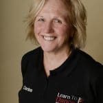Headshot of Denise Bainton, wearing a black polo shirt with her name on the right breast and the Learn To Dance logo and website on the left breast