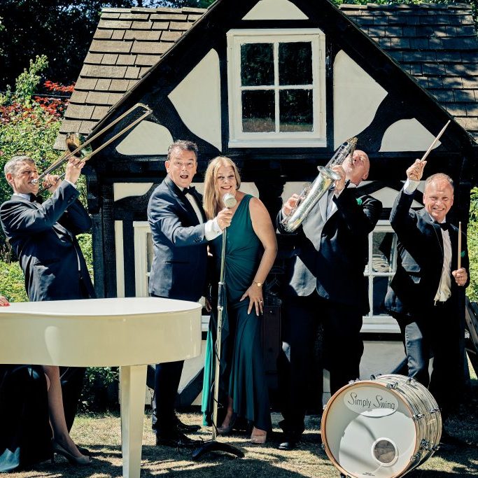 Photo of the Simply Swing Band, Ballroom & Latin American dance singers. A lady at a grand piano, a trombone player, singers, Saxophonist and a drummer